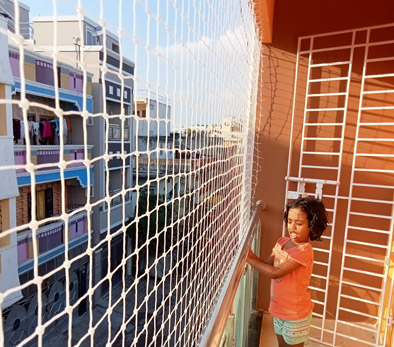 Child beside a balcony safety net on an apartment balcony