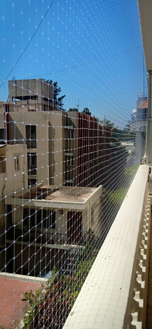 Green bird net installed along a high-rise apartment balcony